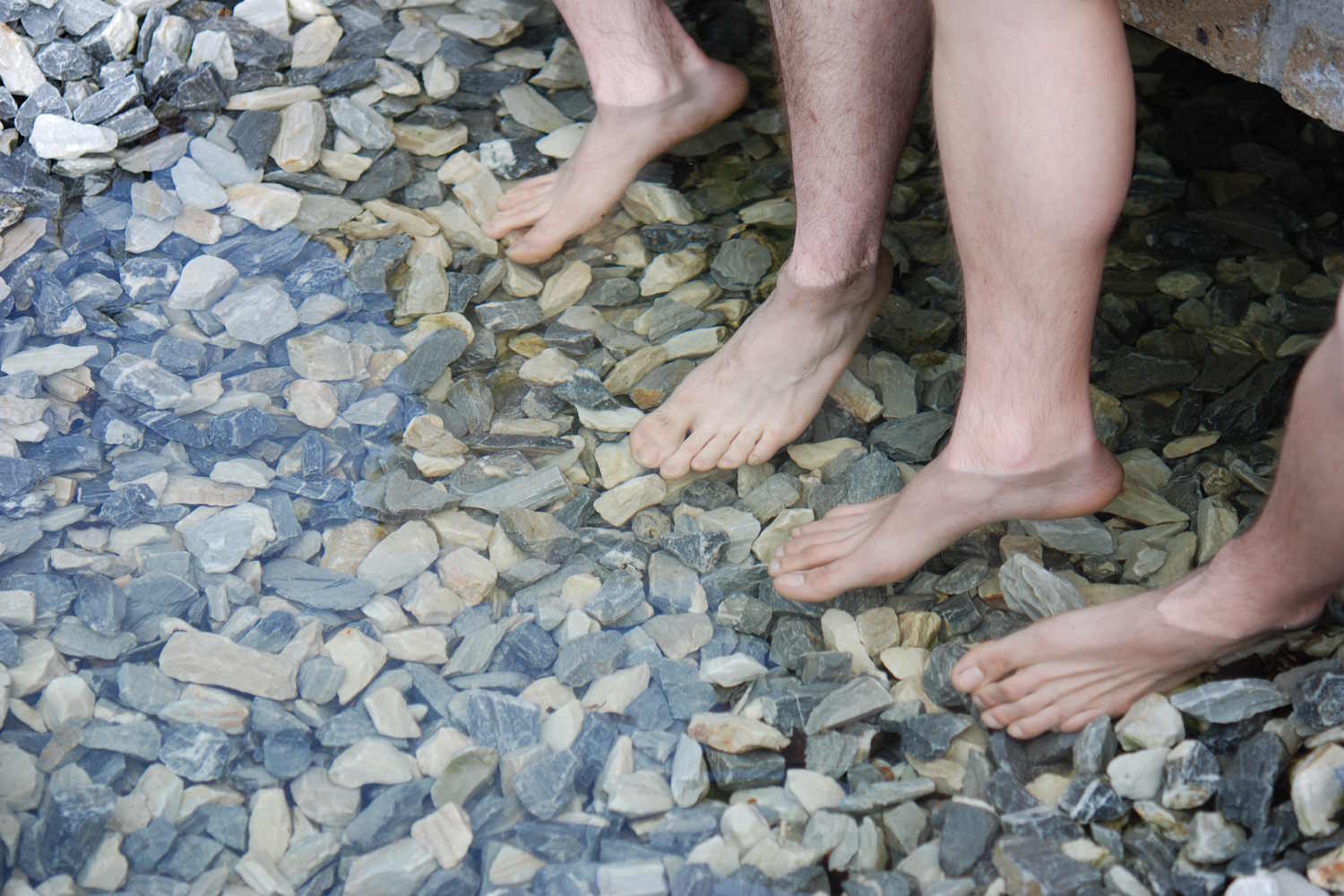 Füße in Wasserbecken mit Steinen an Grund