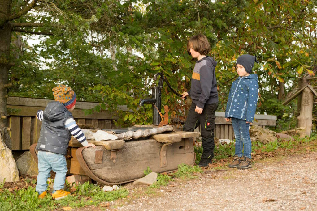 Kinder spielen am Brunnen